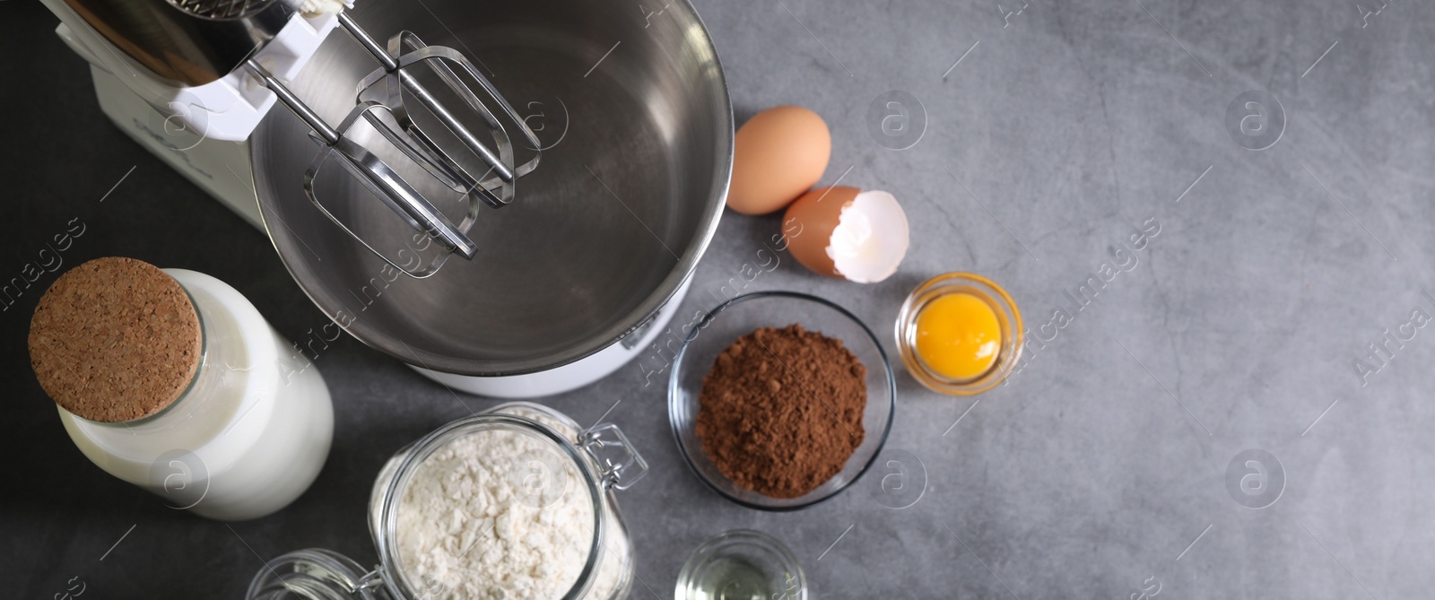 Photo of Stand mixer and different ingredients for dough on grey table, flat lay. Space for text