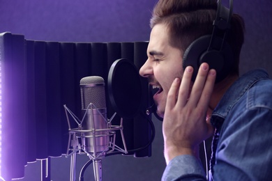 Photo of Young singer with microphone recording song in studio