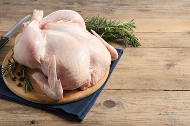 Photo of Fresh raw chicken with spices and knife on wooden table, space for text