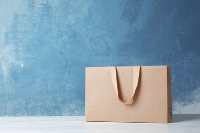 Photo of Paper shopping bag with handles on table against color wall. Mock up for design