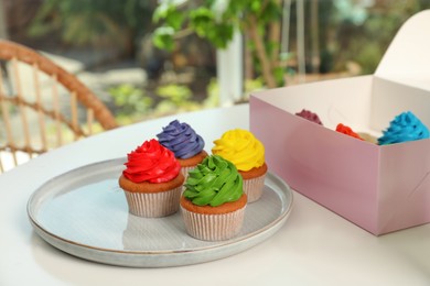 Delicious colorful cupcakes on white table indoors