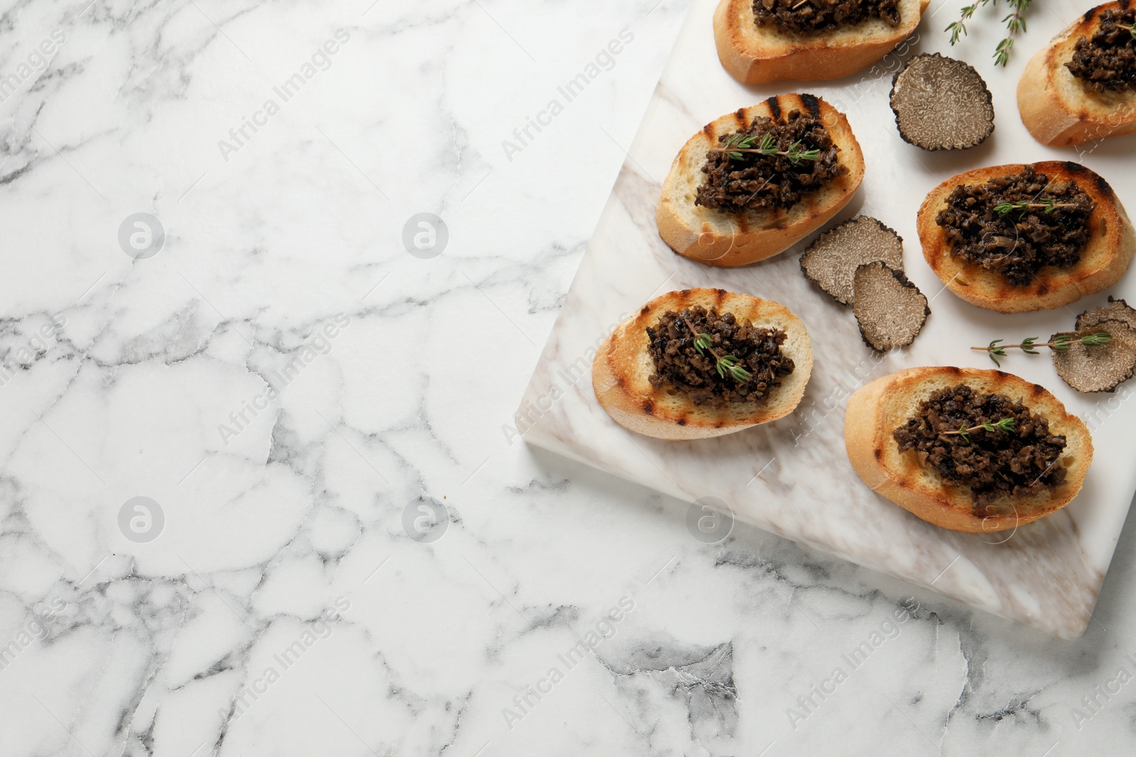 Photo of Delicious bruschettas with truffle sauce and thyme on white marble table, top view. Space for text