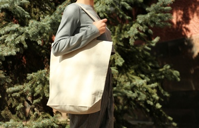 Photo of Young woman with cotton bag on city street, closeup. Mockup for design