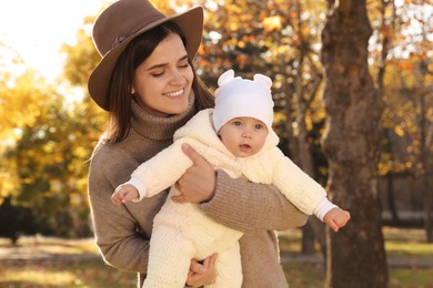 Happy mother with her baby daughter in park on sunny autumn day