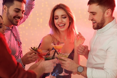 Group of young people holding martini cocktails at party