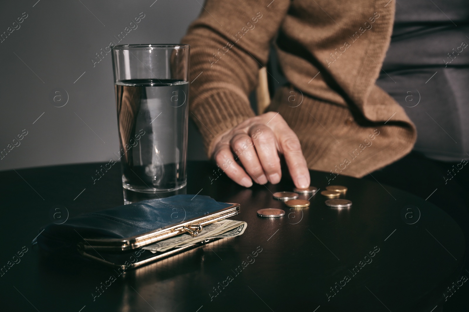 Photo of Poor senior woman with water, wallet and coins at table, closeup
