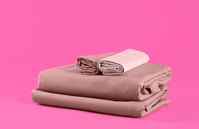 Photo of Stack of clean bed sheets on pink background