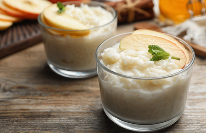 Delicious rice pudding with apple on wooden table, closeup