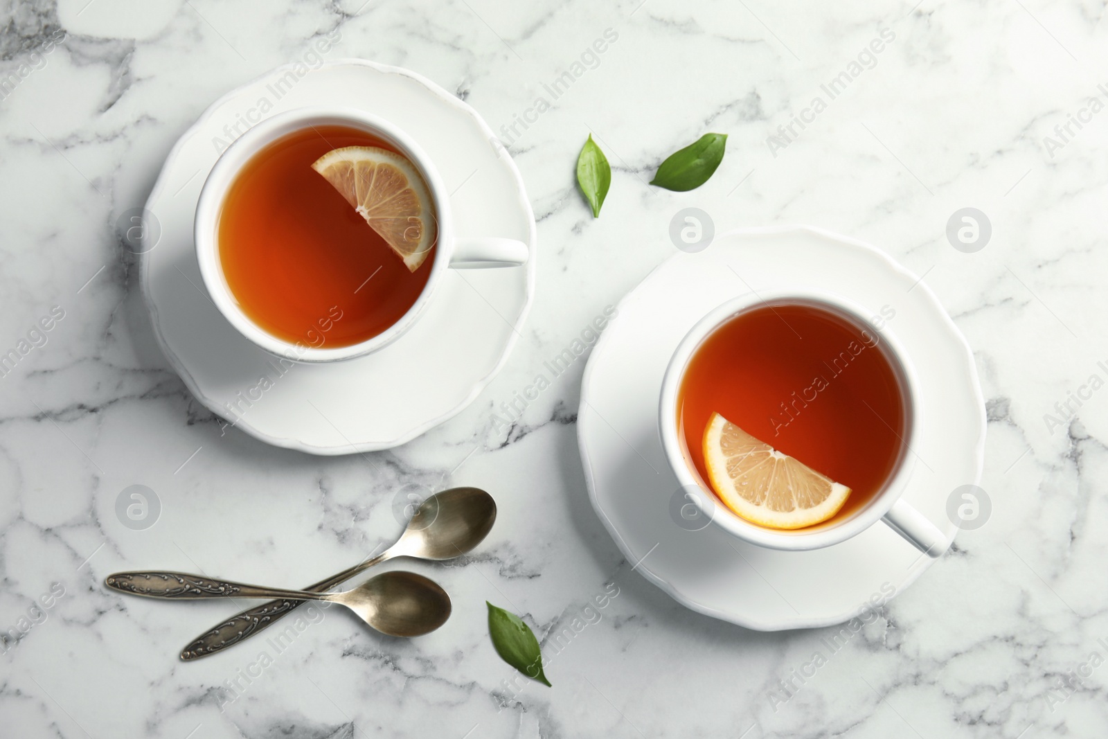 Photo of Cups with black tea and lemon on marble table, top view