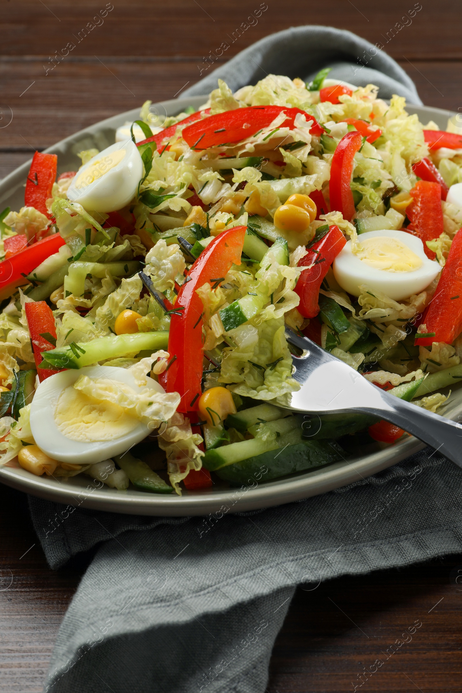 Photo of Delicious salad with Chinese cabbage and quail eggs served on wooden table, closeup