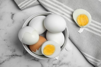 Photo of Hard boiled eggs and kitchen towel on white marble table, flat lay