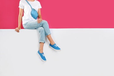 Woman wearing stylish shoes on color background, closeup