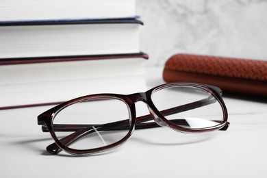 Glasses in stylish frame and books on white table