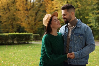 Photo of Romantic young couple spending time together in autumn park, space for text