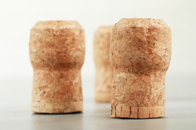 Photo of Corks of wine bottles on light grey table, closeup