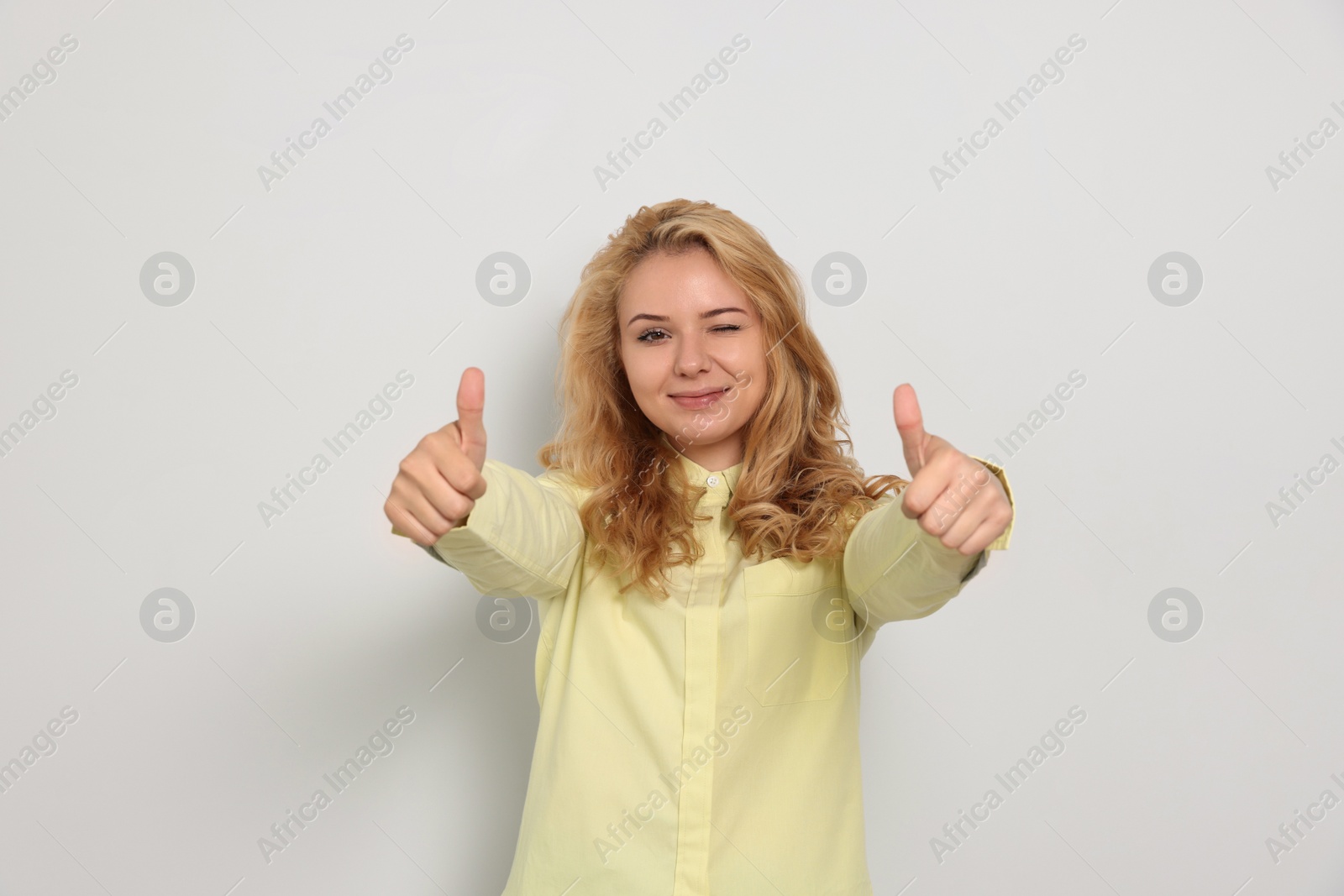 Photo of Happy young woman showing thumbs up on white background