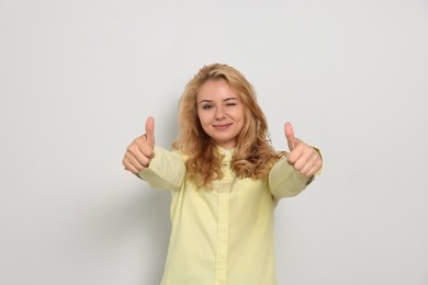 Photo of Happy young woman showing thumbs up on white background