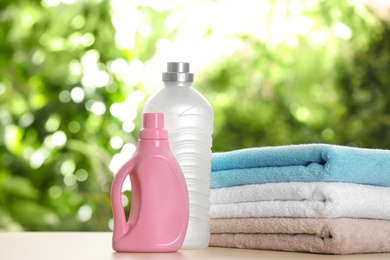 Photo of Soft bath towels and laundry detergents on table against blurred background. Space for text