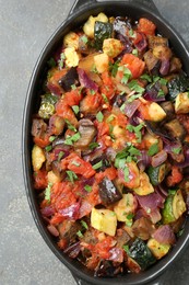 Photo of Dish with tasty ratatouille on grey textured table, top view