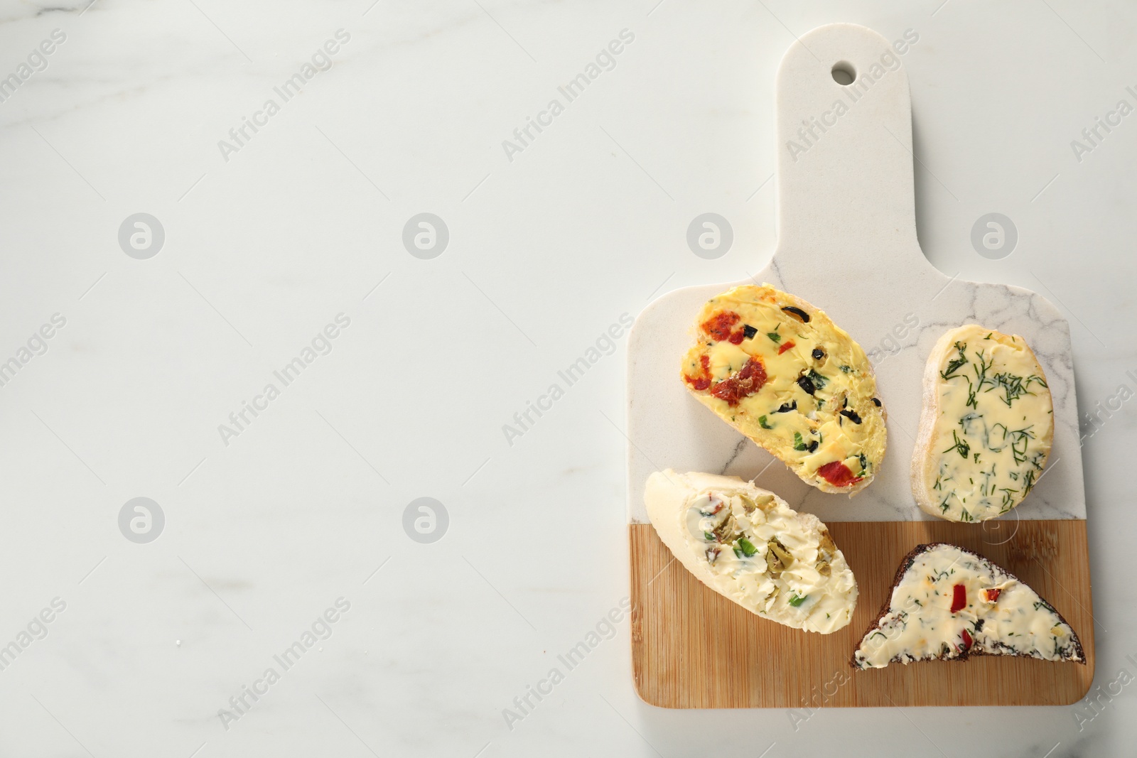 Photo of Different types of tasty butter and bread on white marble table, top view. Space for text