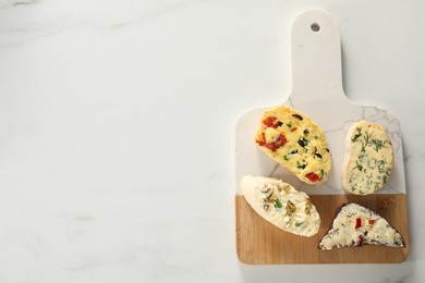 Photo of Different types of tasty butter and bread on white marble table, top view. Space for text