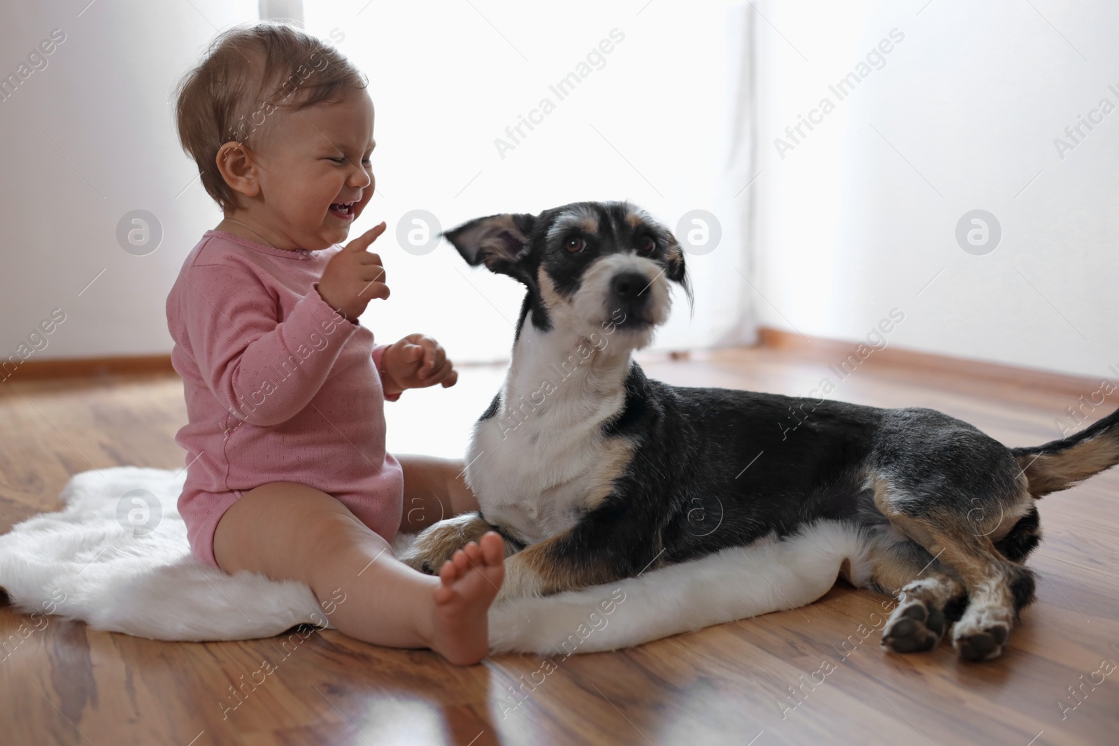 Photo of Adorable baby and cute dog on faux fur rug indoors