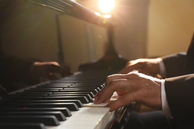Photo of Man playing piano indoors, closeup. Talented musician