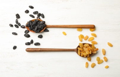 Photo of Flat lay composition with spoons and raisins on wooden background. Dried fruit as healthy snack