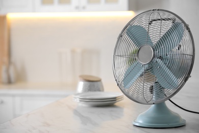 Photo of Modern electric fan on countertop in kitchen, space for text. Summer heat