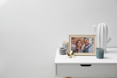 Photo of Framed photo of happy couple and candles on white table indoors. Space for text