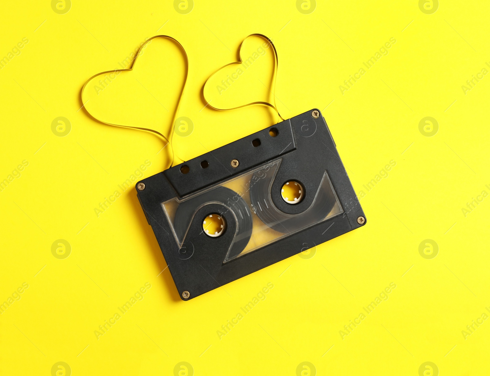 Photo of Music cassette and hearts made with tape on yellow background, top view. Listening love song