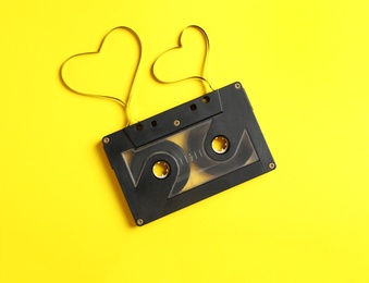 Photo of Music cassette and hearts made with tape on yellow background, top view. Listening love song