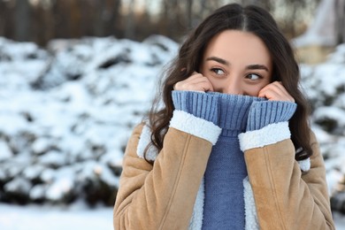 Portrait of young woman in snowy park. Space for text