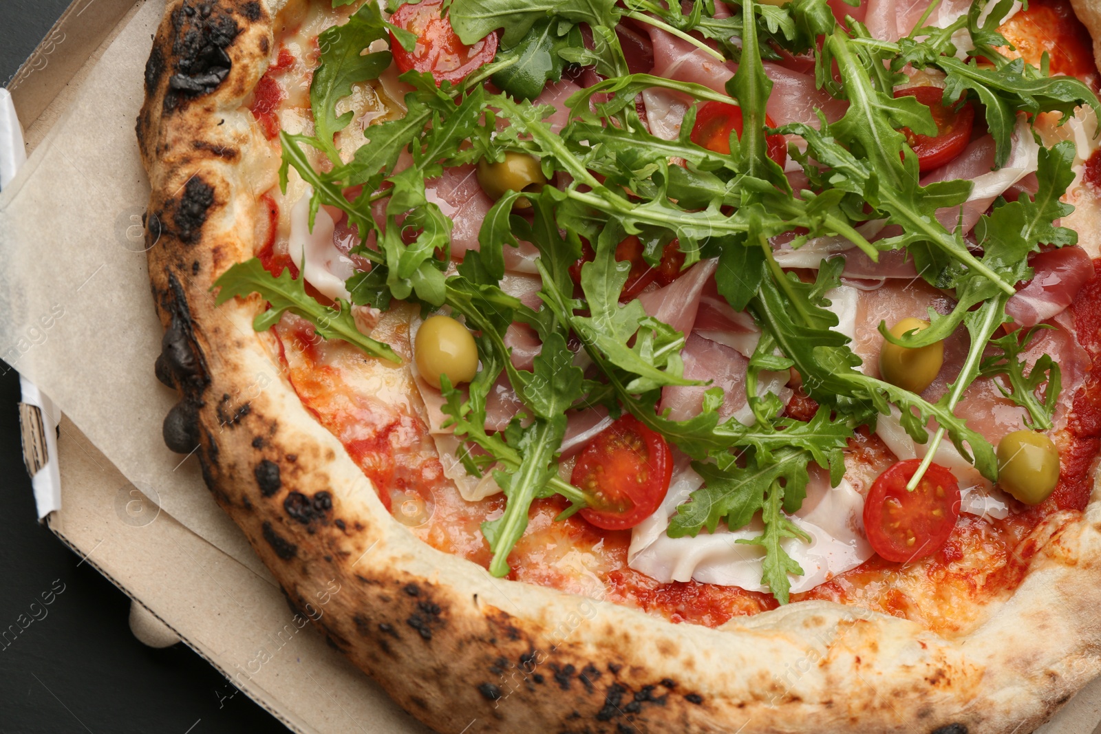 Photo of Tasty pizza with meat and arugula in cardboard box, top view