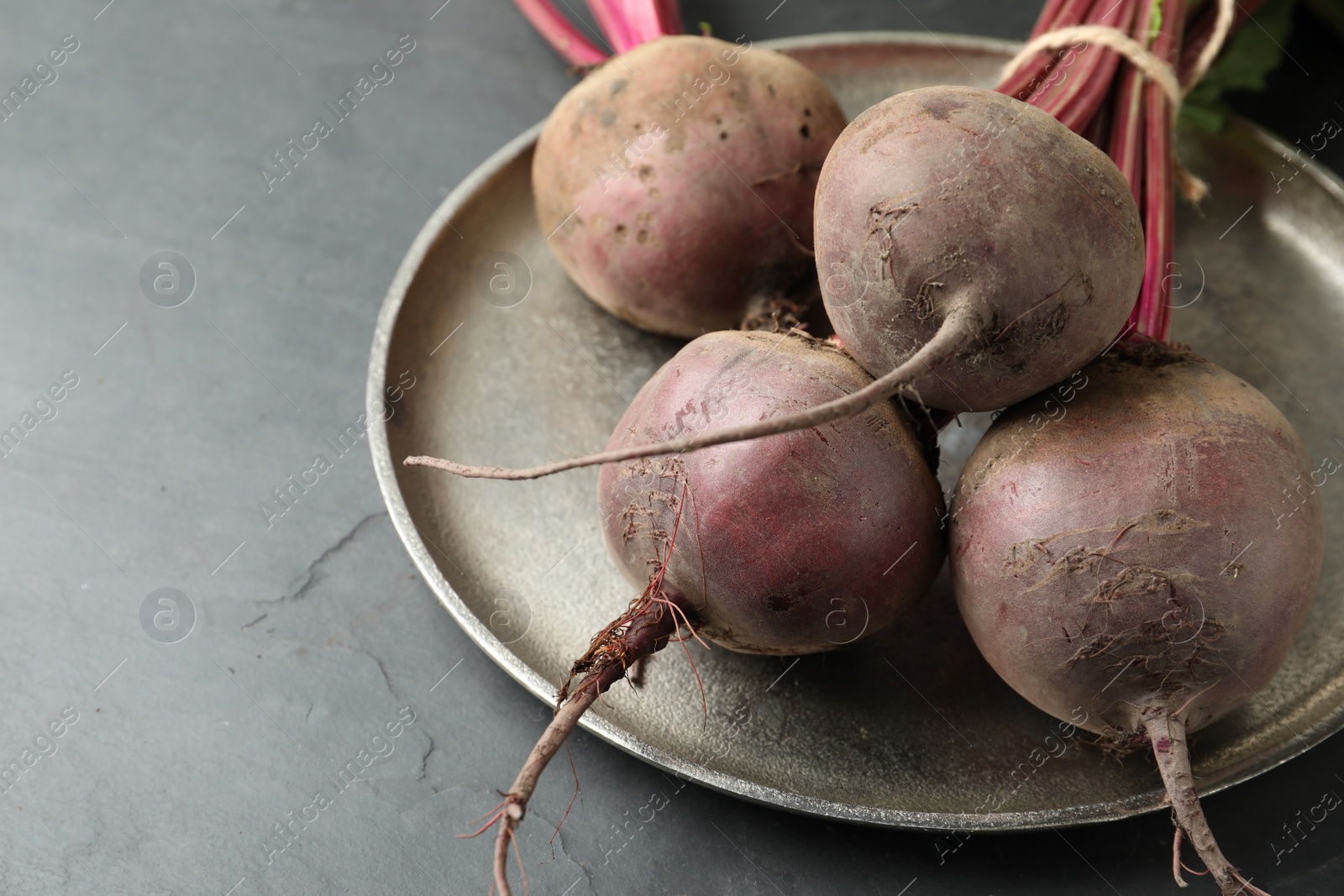 Photo of Raw ripe beets on black slate table, closeup