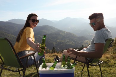 Photo of Couple and cool box with bottles of beer in mountains