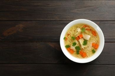 Photo of Homemade chicken soup served on wooden background, top view with space for text