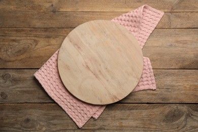 Pink kitchen towel and cutting board on wooden table, top view