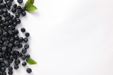 Ripe bilberries and leaves on white background, flat lay. Space for text