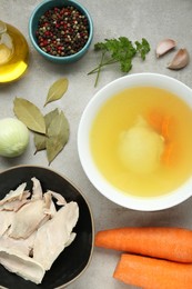 Delicious chicken bouillon and ingredients on light grey textured table, flat lay