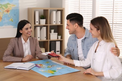 Travel agent giving tickets and passports to clients in office