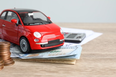 Photo of Toy car and money on table, space for text. Vehicle insurance