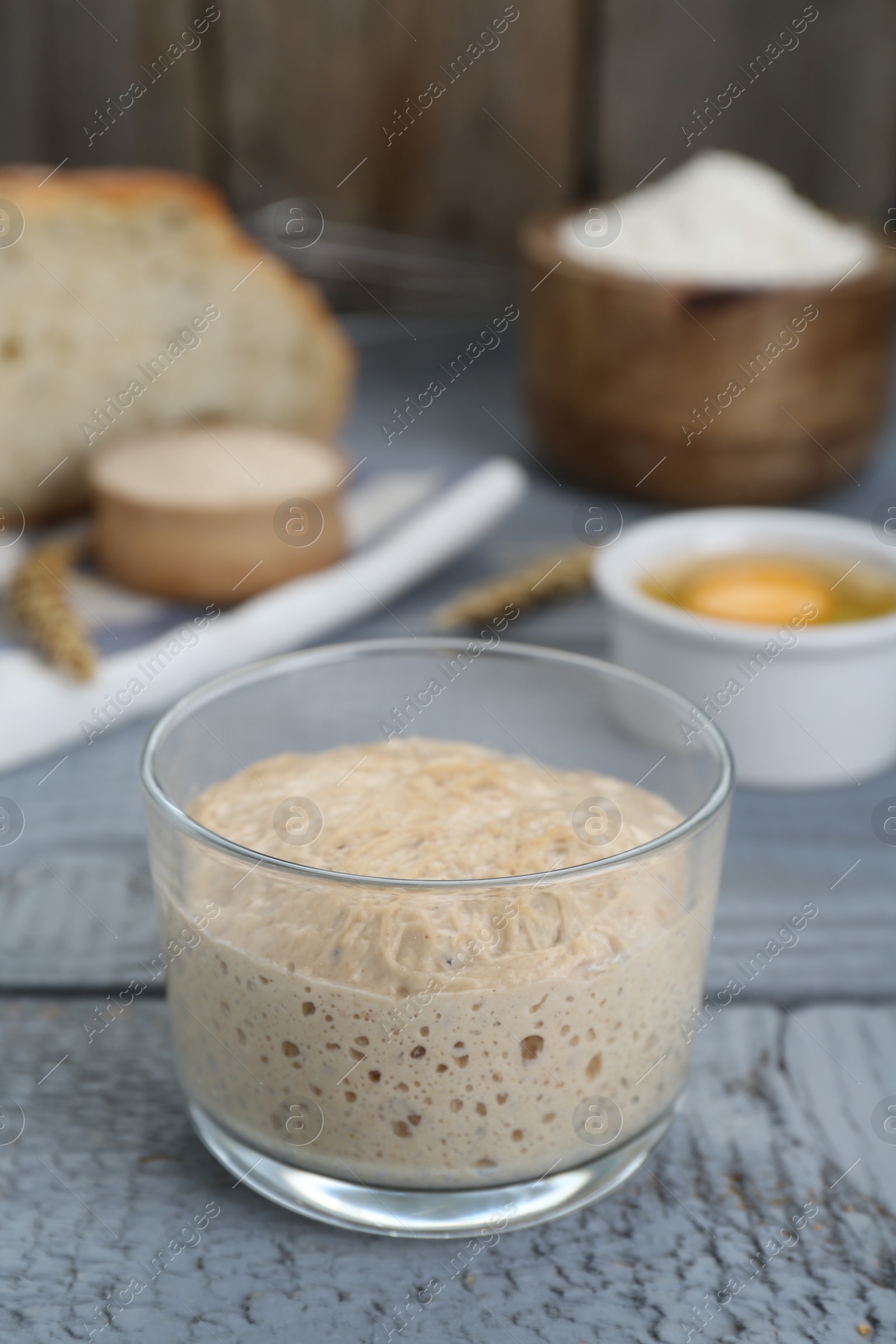 Photo of Glass jar with sourdough on grey wooden table
