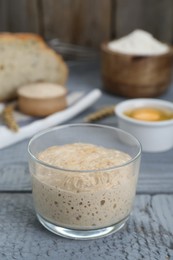 Photo of Glass jar with sourdough on grey wooden table