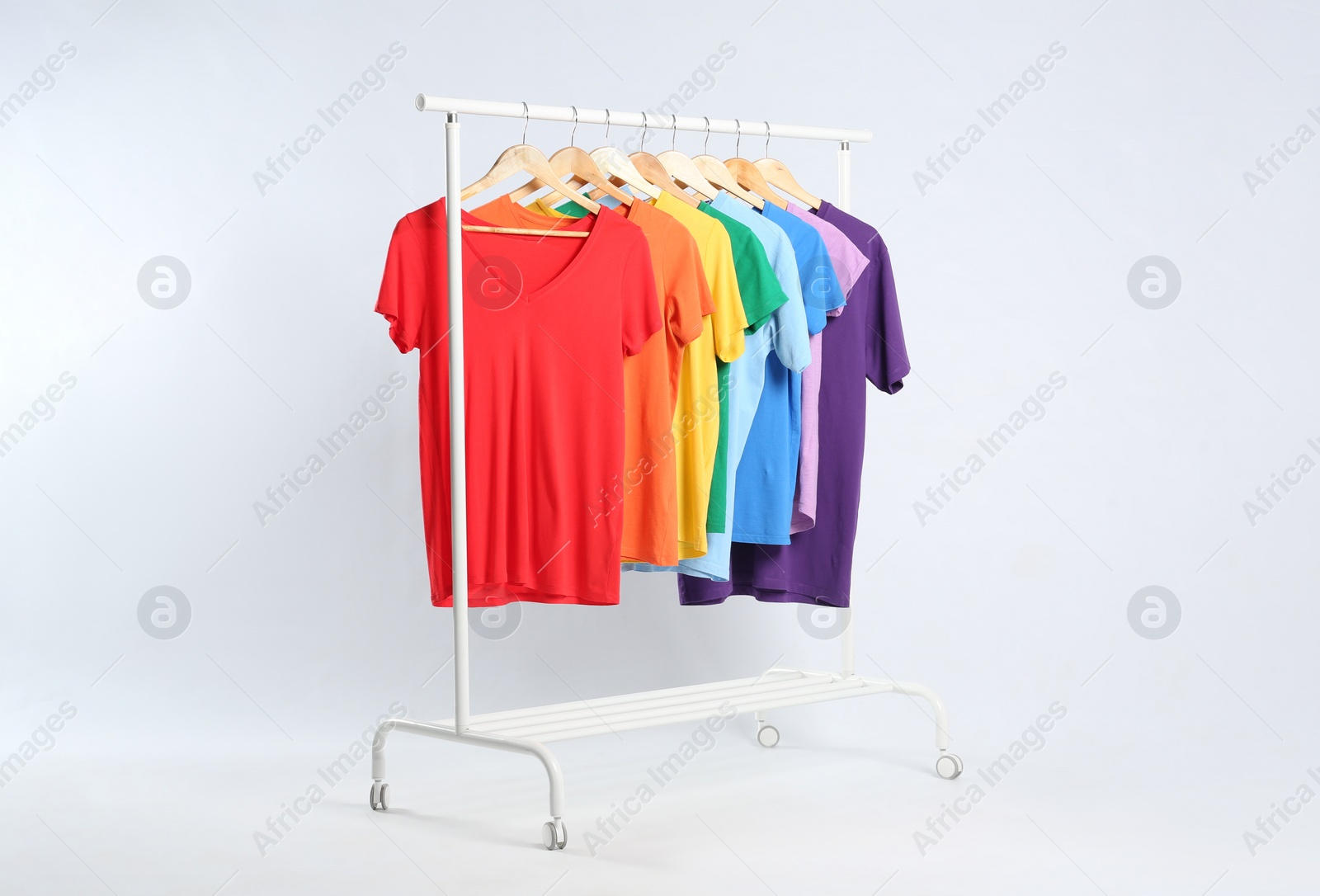 Photo of Colorful clothes hanging on rack against white background