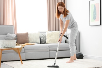 Housewife hoovering carpet at home