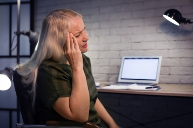 Overworked mature woman with headache in office