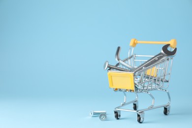 Photo of Different construction tools in shopping cart on light blue background, space for text