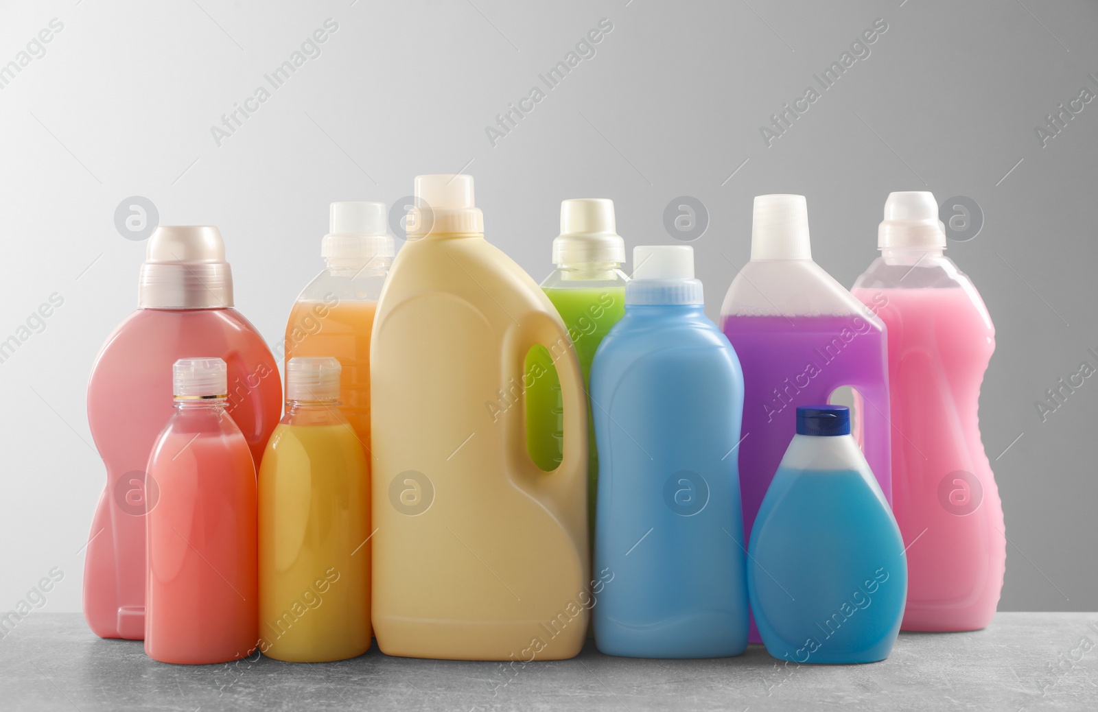 Photo of Different bottles with detergents on grey table