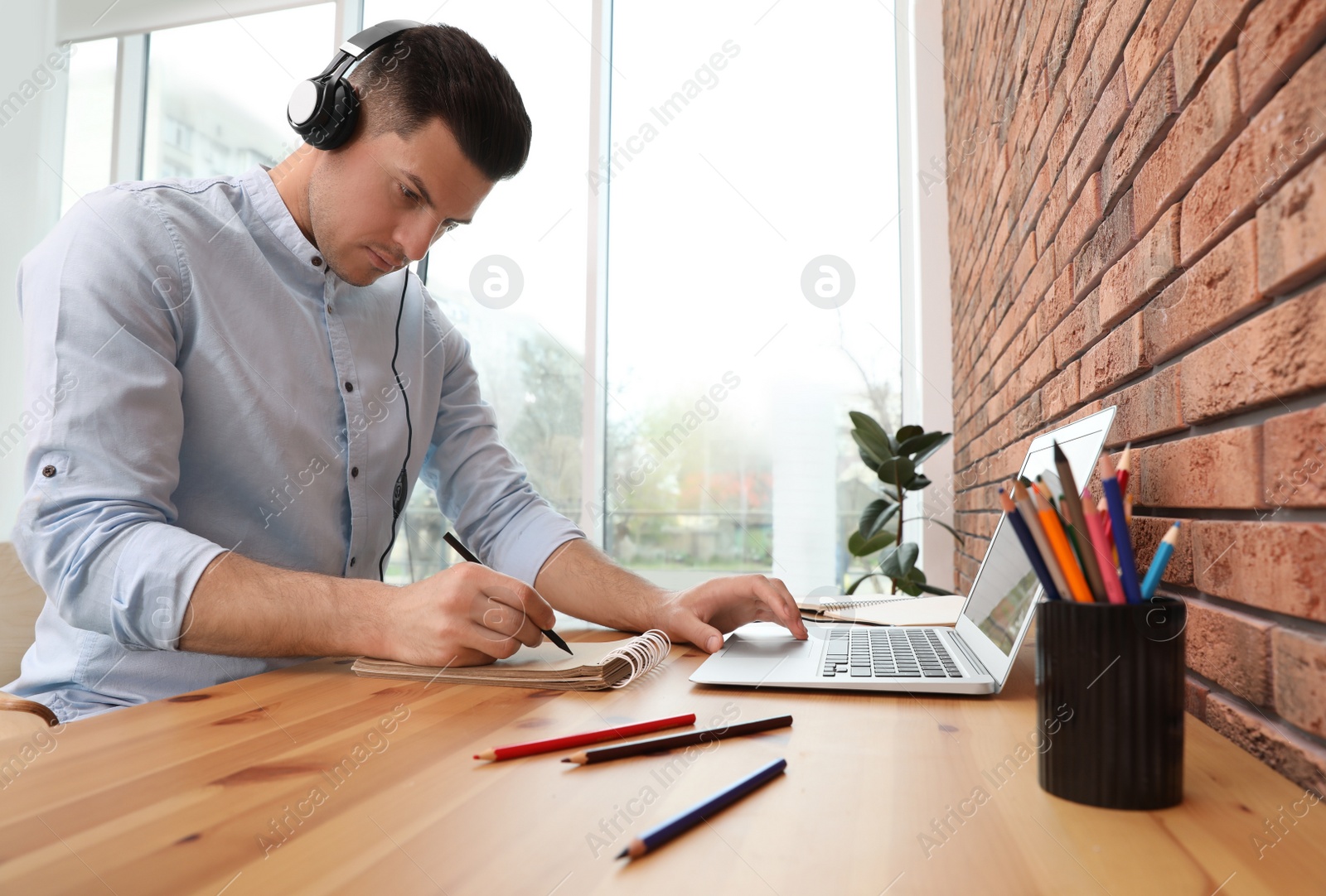 Photo of Man drawing in notebook at online lesson indoors. Distance learning